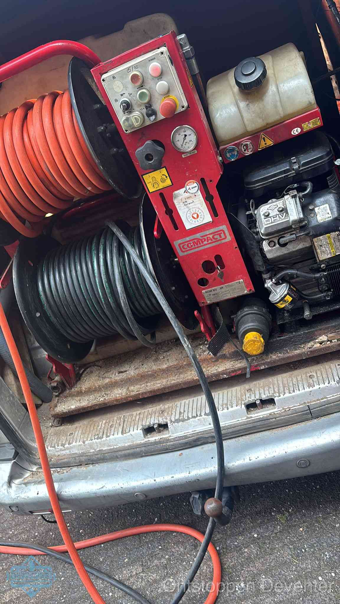 Een rood hogedruk-rioolreinigingstoestel met slangen in de laadbak van de bedrijfsbus, apparatuur voor een hardnekkige wc-verstopping in Deventer