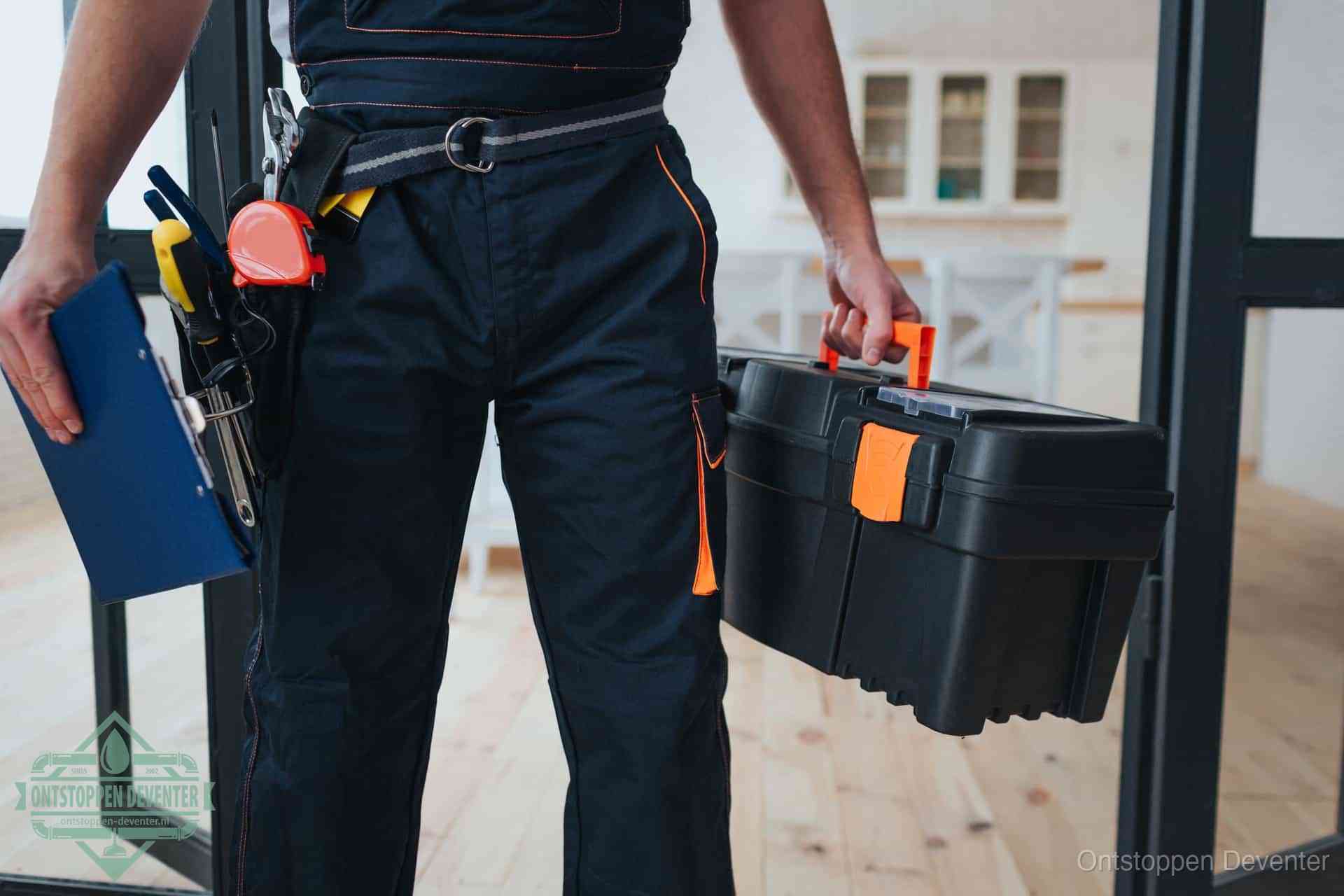 Een monteur met gereedschapsriem en klembord, klaar om een transparante prijs voor het afvoer ontstoppen in Deventer te geven