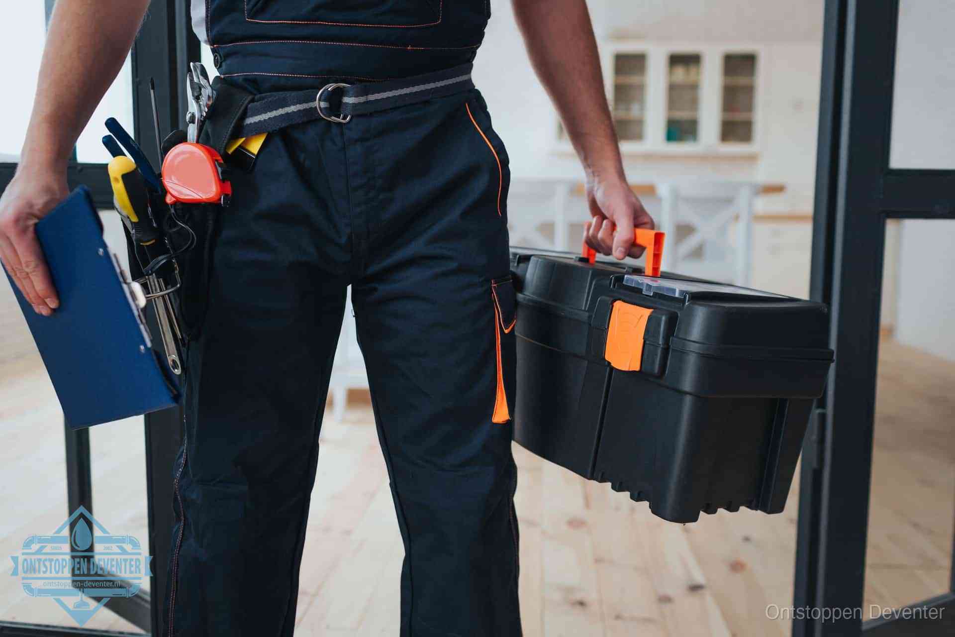 Een monteur met gereedschapsriem en klembord in een keuken, klaar om een transparante prijs voor het gootsteen ontstoppen in Deventer te geven