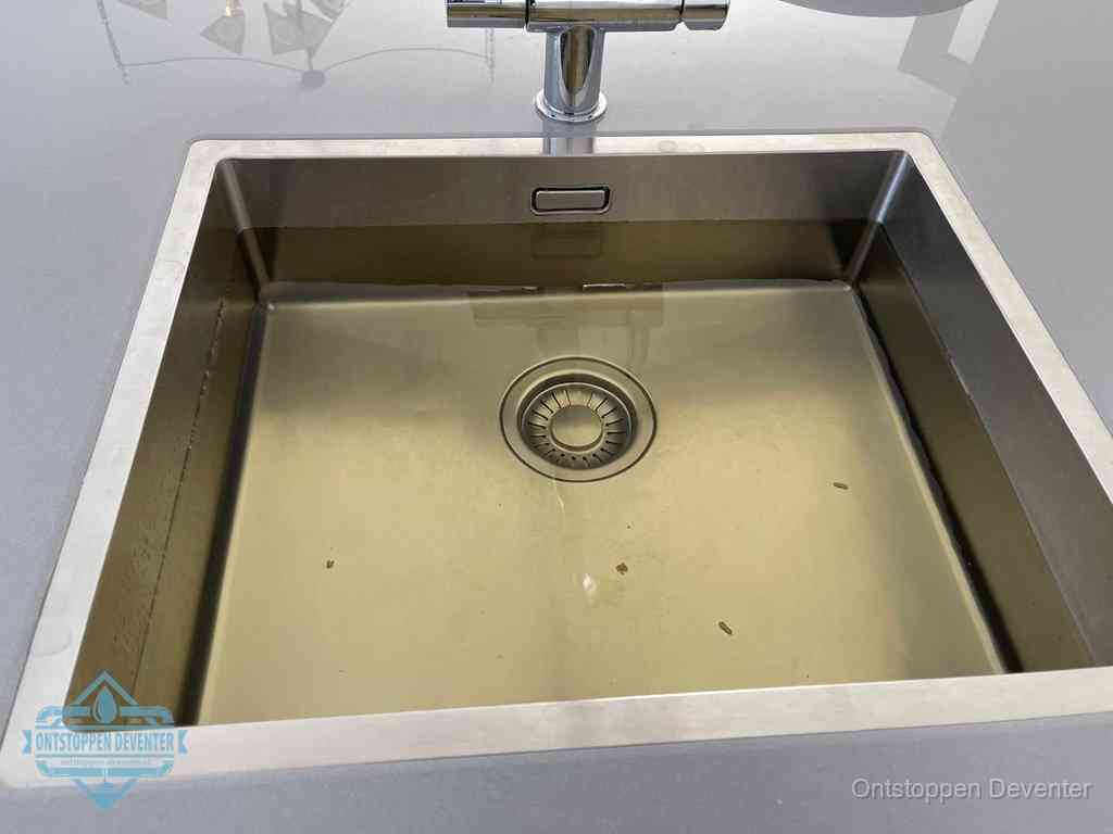 Stilstaand water in een rvs spoelbak dat niet wegloopt, een duidelijk signaal van een gootsteenverstopping in Deventer