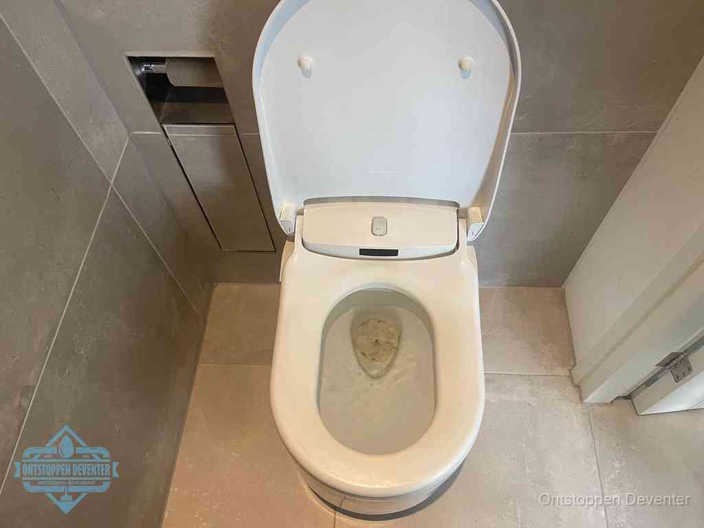 Een wit hangtoilet waarin een prop wc-papier op het water blijft drijven, een duidelijk signaal van een verstopte wc in Deventer