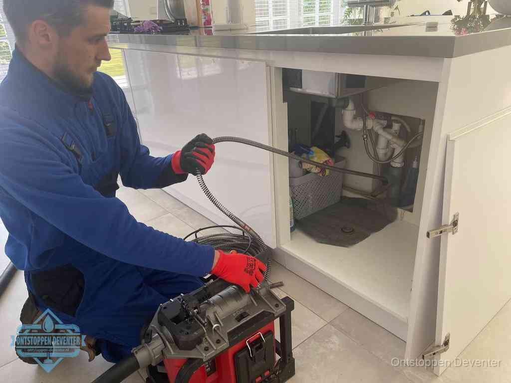 Een monteur reinigt de keukenafvoer grondig met een veermachine om terugkerende gootsteenverstoppingen te voorkomen in Deventer