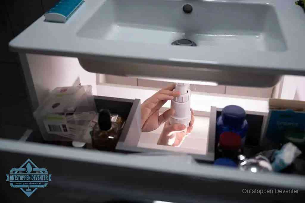 Een pompfles met zeep boven een wastafel in de toiletruimte, de warm water en afwasmiddel-methode om de wc te ontstoppen in Deventer