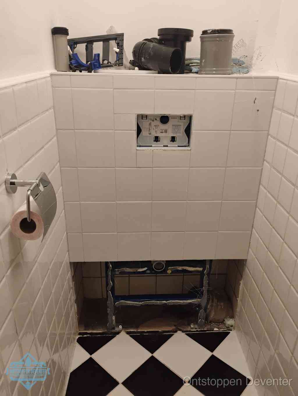 Een toiletruimte waar het hangtoilet en de inbouwreservoir-onderdelen zijn vrijgelegd voor onderhoud, periodiek nazicht voorkomt een wc-verstopping in Deventer