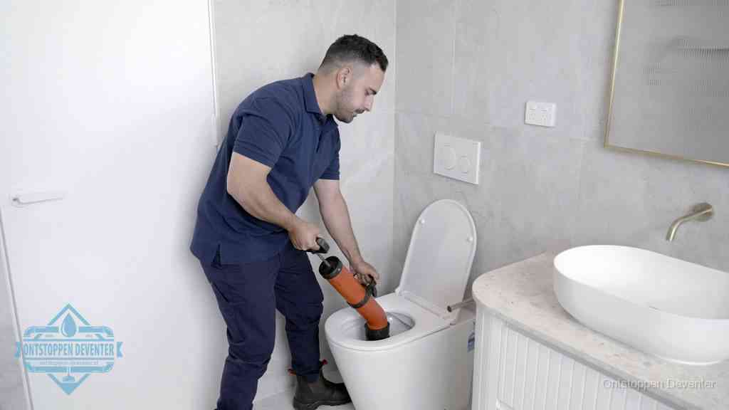 Een monteur gebruikt een handmatige perspomp (toiletontstopper) op een wandcloset tijdens het professioneel wc ontstoppen in Deventer